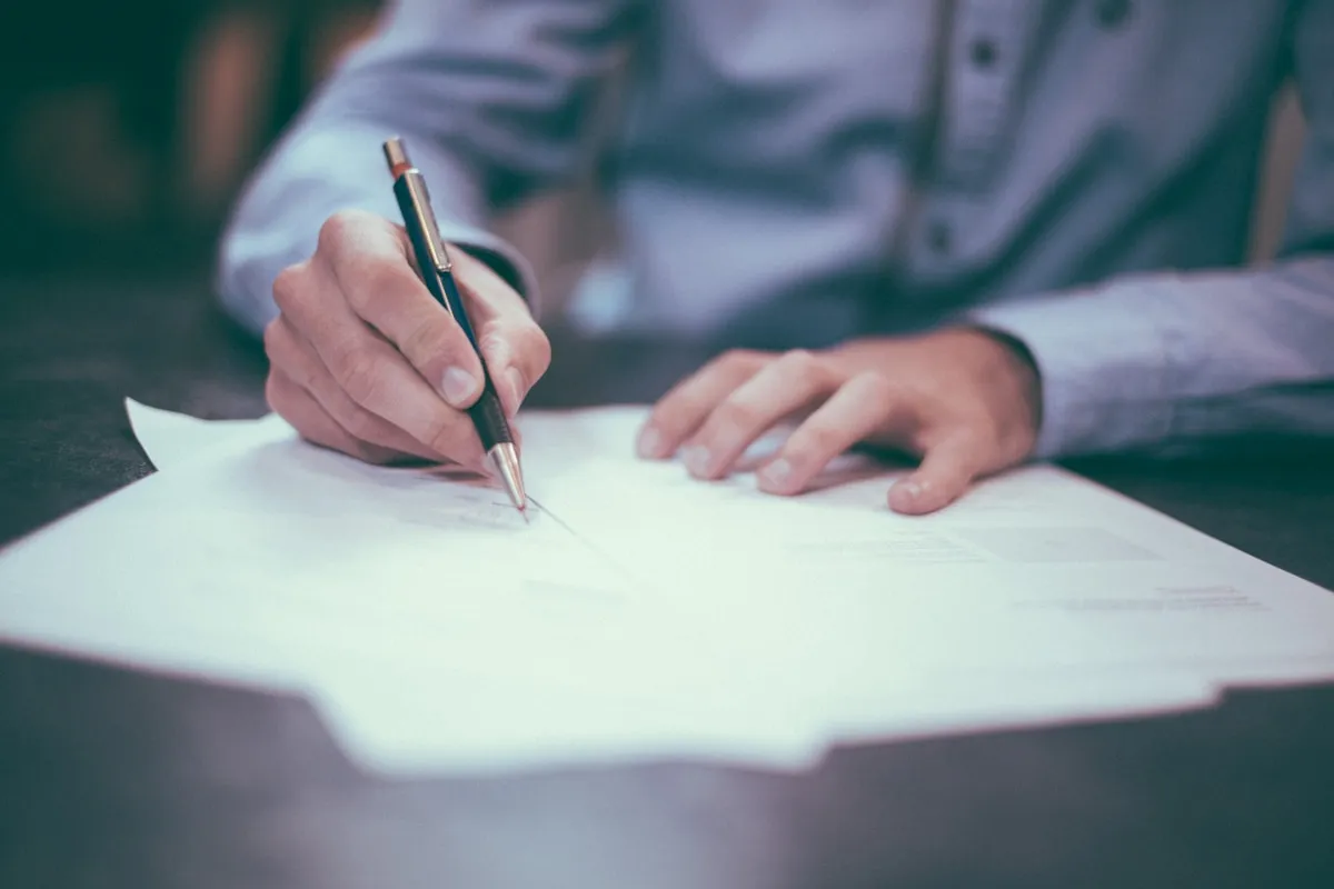 A trustee signing trust documents at a desk, representing the formal obligations of fiduciary duty